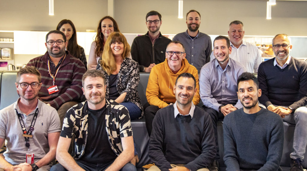 Group of Swansea customer centre employees sitting and smiling.