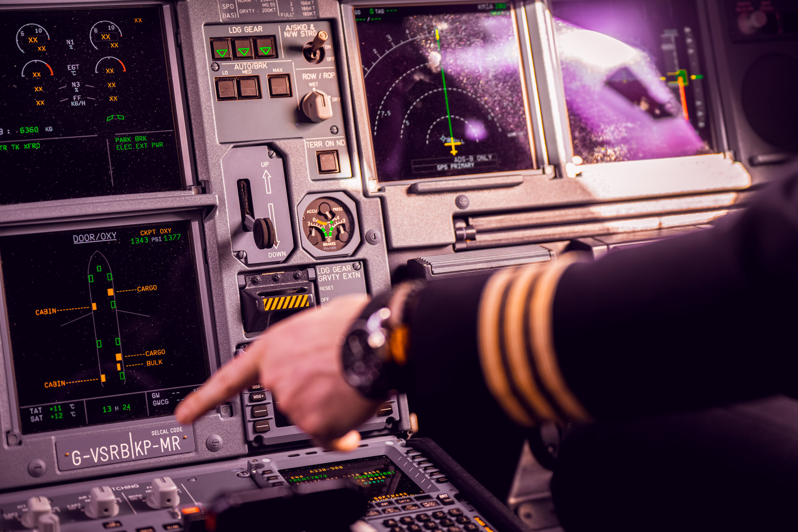 In a Virgin Atlantic cockpit, a man points at a computer, engaged in monitoring flight data and systems
