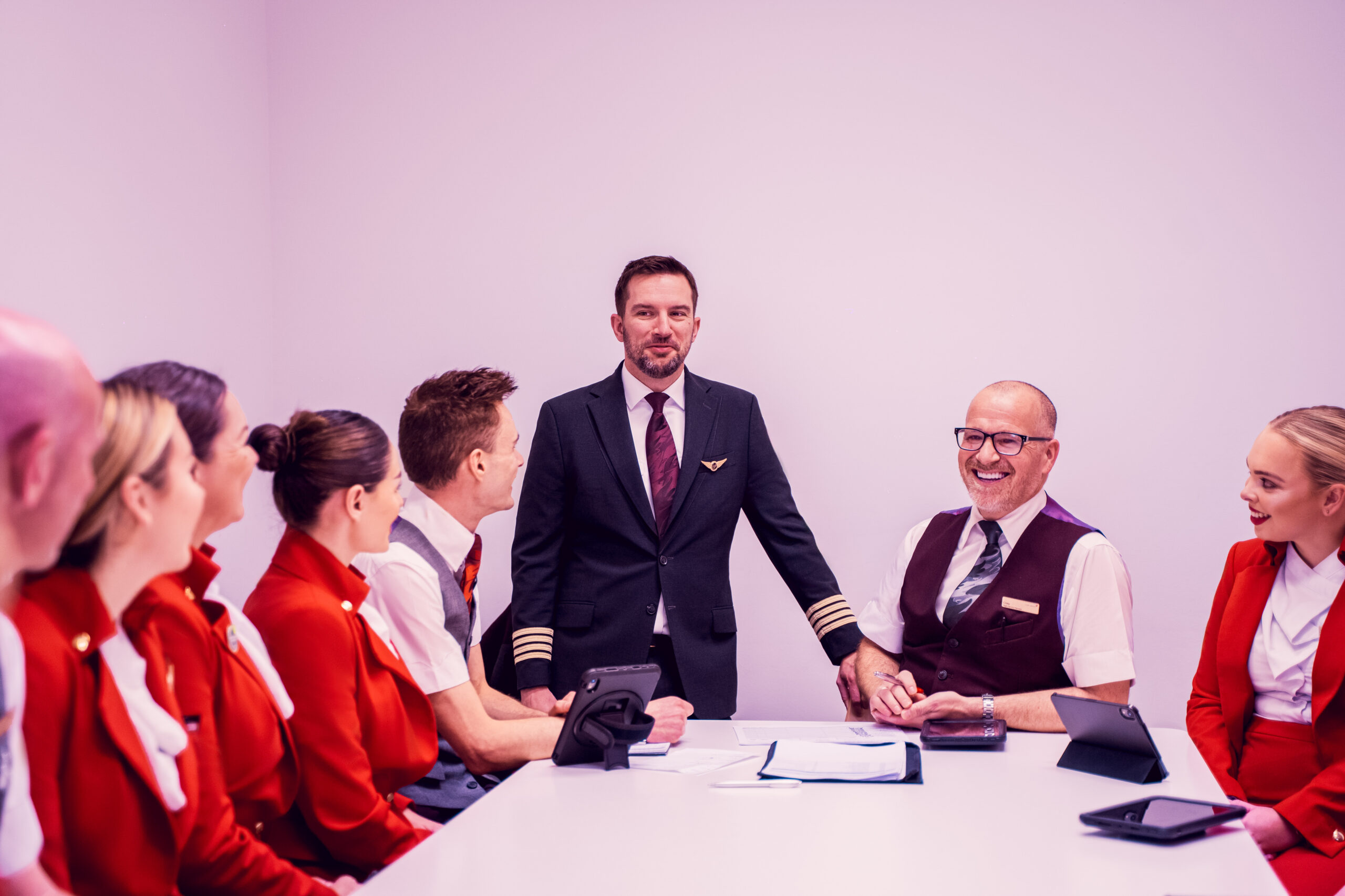 A group of people in Virgin Atlantic uniforms seated around a table, engaged in discussion