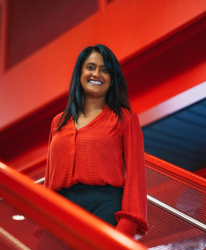 Virgin Atlantic employee smiling on stairs while wearing red