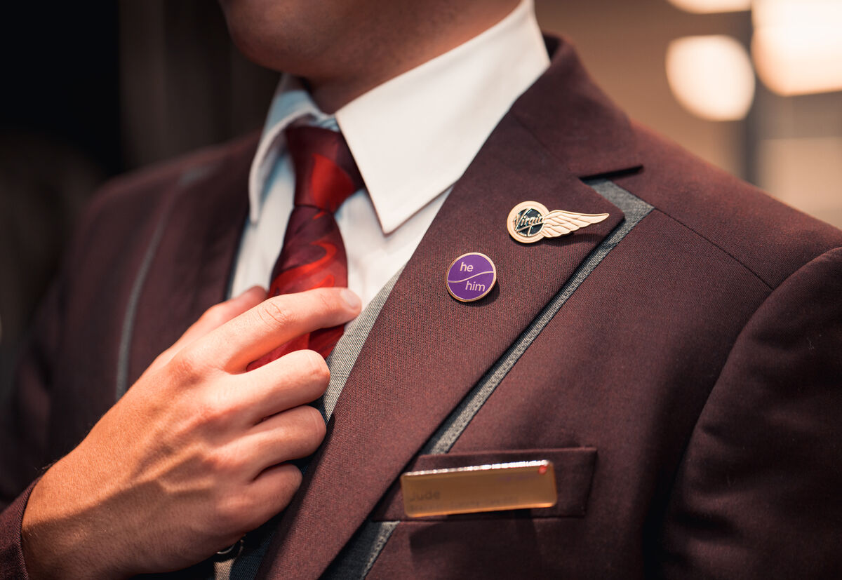 Virgin Atlantic employee wearing a he/him pronoun badge